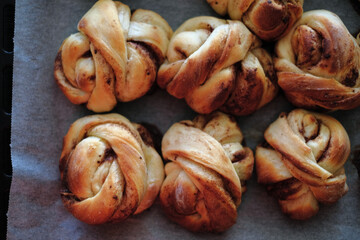 Freshly baked cinnamon buns on a baking sheet with paper	
