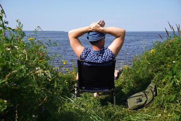 Tourist relaxing in folding chair by lake enjoying scenic view