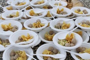 Multiple Bowls of Asian Noodles with Meatballs and Crispy Wontons in White Plates