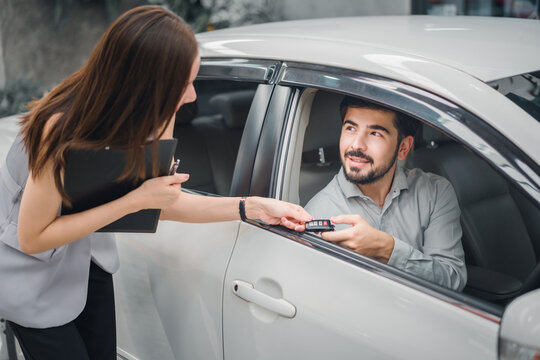 Car sales agent handing key to customer inside new car, showing final delivery moment, trusted service, professional consultation, and customer satisfaction in automotive purchase process.