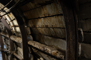 Rusty steel arches and concrete block lining inside a mine service tunnel, with timber lagging and...