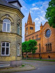 St. Paul's Church at Sankt Pauls Plads in Copenhagen’s Nyboder district, framed by yellow buildings, cobblestone streets, and trees under a partly cloudy sky.