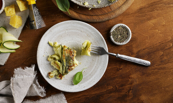 A plate with a piece of Vegetable zucchini round pie on the ceramic plate on wooden background, top view - Powered by Adobe