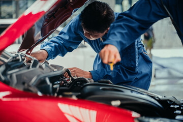 Blue-uniform mechanic team inspecting red car engine in workshop, symbolizing teamwork, professional service, and quality check in automotive repair.