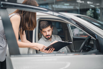 Customer sitting in new car signing agreement with sales agent, symbolizing trust, professional service, and successful automotive purchase.
