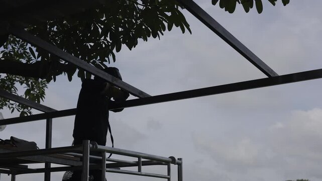 Welder Is Joining Steel Beams For The Roof, Master welder expertly fuses steel beams for a robust roof, capturing the essence of industrial craftsmanship in a stunning construction documentary scene.