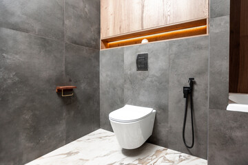 A bathroom with a toilet, bathtub, and sink. The bathroom has a modern design with a wooden...