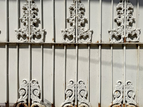 Close up of white wrought iron trellis in random floral swirls and ornamental pattern. Suitable for fence and front gate of a house. Seamless background texture
