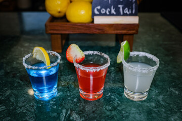 Colorful tequila shots with fruit garnishes and salt rim
