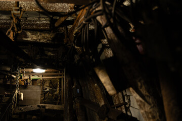 Dimly lit mining tunnel with ventilation pipes, cables and belt conveyor in an abandoned coal mine,...