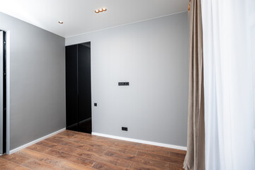 A room with a white wall and a black door. The room is empty and has a minimalist feel