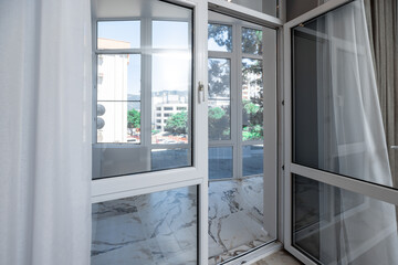 A large window in a building with a view of a city. The window is dirty and the view is obscured by...