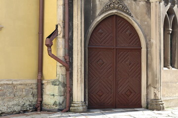 Wooden door with intricate carvings situated beside a yellow stone wall in a historic European town...
