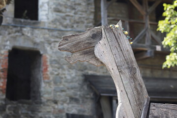 Wooden horse sculpture near historic stone building during sunny daytime in a rural setting