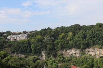 Obraz premium Scenic view of lush green hillside and residential buildings along the cliffside in daylight