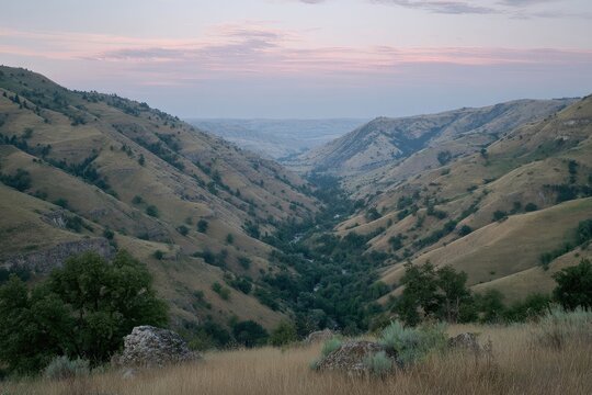 Mountain valley at twilight. Vast, sloping hills meet a narrow river valley - Powered by Adobe