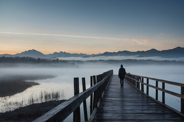 Obraz premium Serene mist walk silhouette on wooden pier in foggy mountain landscape