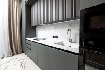 A kitchen with a black oven and microwave. The kitchen is very clean and organized. The white...