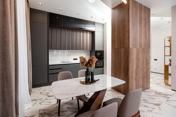 A kitchen with a white counter and a black cabinet. A vase with flowers on the counter