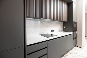 A kitchen with a white countertop and black cabinets. The cabinets are made of wood and the...