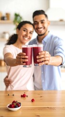 Smiling couple in kitchen showcasing berry smoothies
