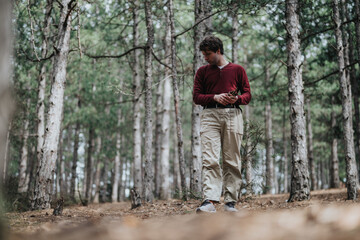 A man standing among lush green trees in a serene forest setting, embracing nature.