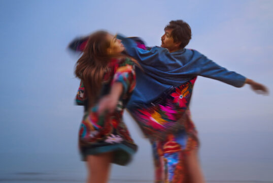 Dancing figures in colorful patchwork robes with motion blur outdoors