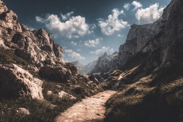 Obraz premium Mountain path winding through a rocky valley under a partly cloudy sky