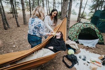 A group of friends relax in a forest campsite with tents and a hammock, creating a peaceful and fun...