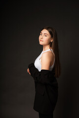 Girl in a pantsuit in the studio on a black background