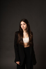 Girl in a pantsuit and a short top in the studio on a black background