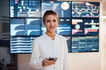 Healthcare professional using mobile phone in front of medical data screens