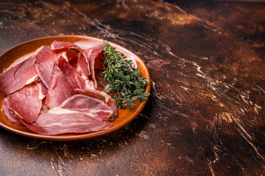 Balkan Prsut prshut, sliced cured pork meat ham on plate. brown background. top view