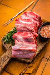 Raw beef Short chuck Ribs, fresh meat with bone on cutting board. orange background. top view