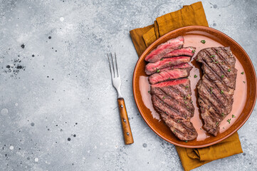 Tender flat iron steak, grilled to enhance its natural flavors and tenderness. grey background. top...