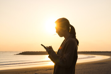 Woman using phone silhouette during sunset time