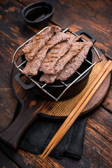 Flavorful yakiniku with juicy wagyu beef slices cooked right at the table. wooden background. top view
