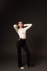 woman in black pants and white sweater on black in studio