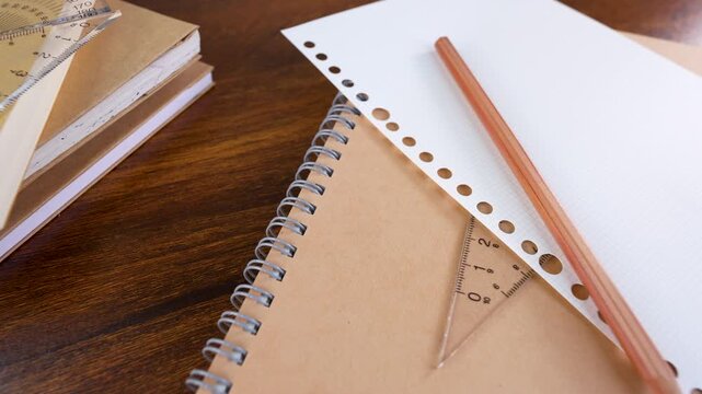 Closeup of protractor, triangle ruler measuring tools, pencil isolated on books and white graph chart paper.