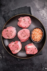 Tender fresh pork medallion, raw tenderloin meat perfect for elevating your dinner table with a touch of culinary finesse. black background. top view