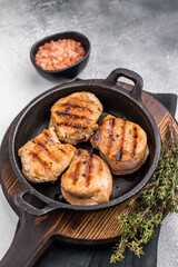 Juicy grilled pork medallions steaks, perfectly seared tenderloin meat for a flavorful bite, ideal for any gourmet meal. grey background. top view