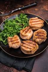 Savory charred pork loin medallion, tenderloin meat showcasing its tender texture and rich flavors after grilling. brown background. top view