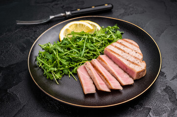 Succulent grilled tuna steak, showcasing vibrant color and rich taste, perfect for summer barbecues and elegant dinners. black background. top view