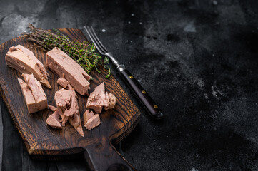 Chunky tinned tuna served on a wooden board, perfect for meal prep or easy weeknight dinners. black background. top view