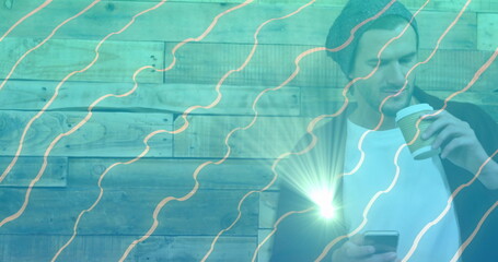 Holding coffee cup and checking smartphone, man in knit beanie at café lounge, copy space