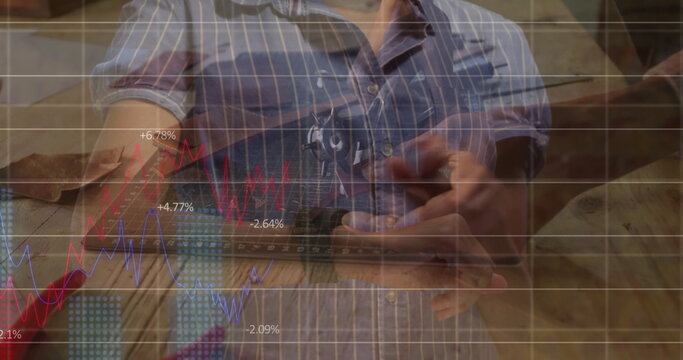 Holding smartphone, Black carpenter viewing line chart on workshop bench with tools in pocket