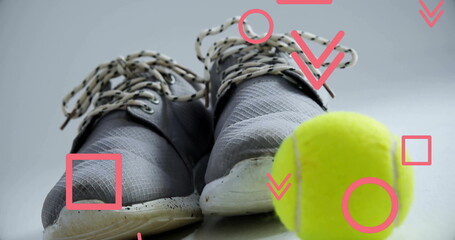 Displaying grey athletic shoes on studio backdrop, with yellow tennis ball and red graphic shapes