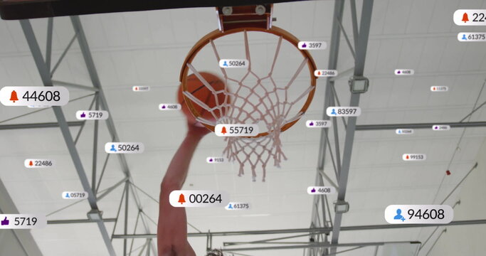 Shooting athlete lifting basketball through hoop under gym beams, with floating social media icons