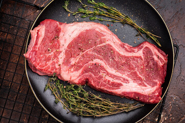 Chuck eye roll steak, raw marbled beef meat  with herb for cooking. brown background. top view