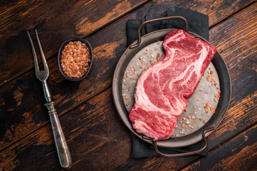 Prime Raw Chuck eye roll steak, fresh beef meat in steel tray. wooden background. top view